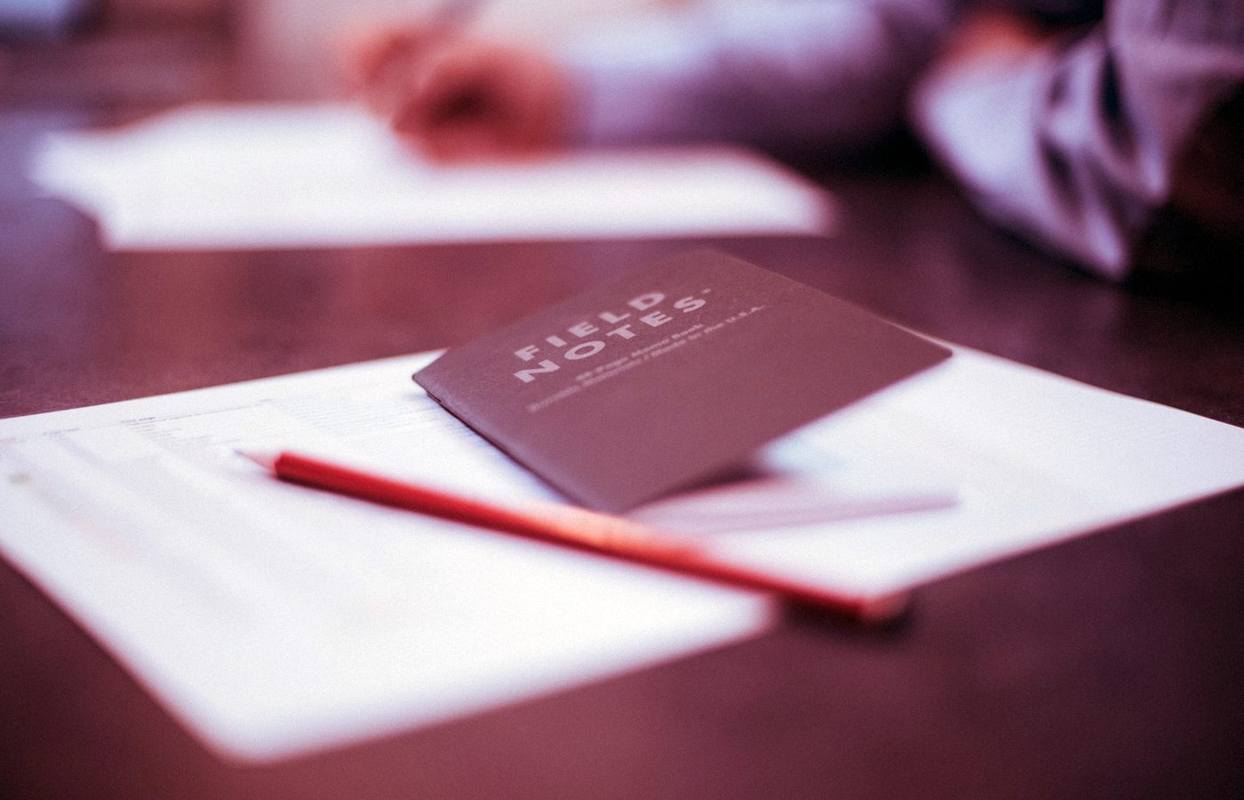 Carnet et crayon posés sur une table de travail